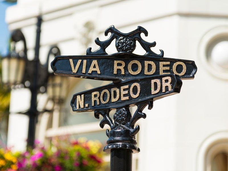 rot iron street signs that read N. Rodeo Dr and Via Rodeo