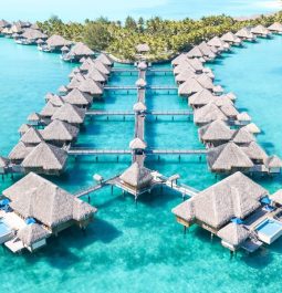 line of overwater villas and blue water at st regis