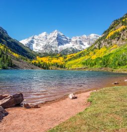 lake with pinkish/red sand and snowy mountain peak in distance