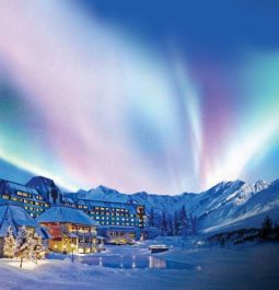 Northern lights shining bright over resort in middle of snow-covered landscape