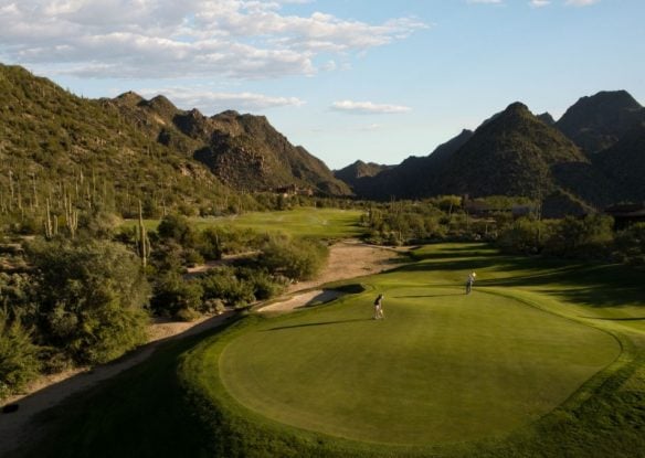 golfers on a golf course surrounded by mountains