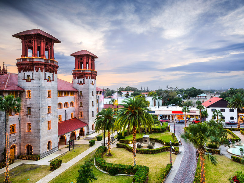 green park with palm trees and historic building with two towers overlooking it