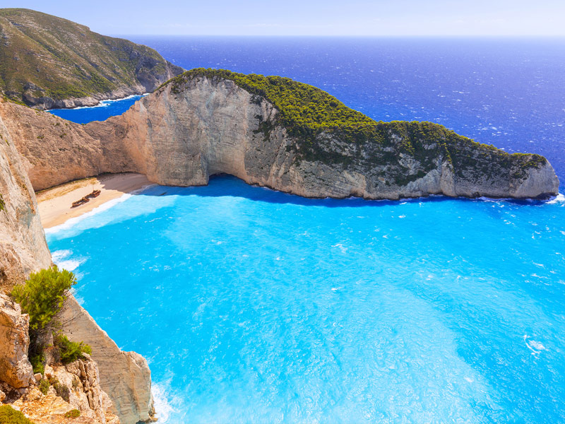 turquoise bay with small beach surrounded by rocky coastline