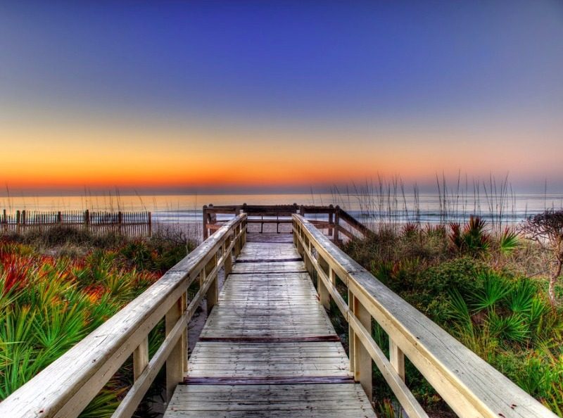 wooden pathway leading out ot beach with beautiful sunset