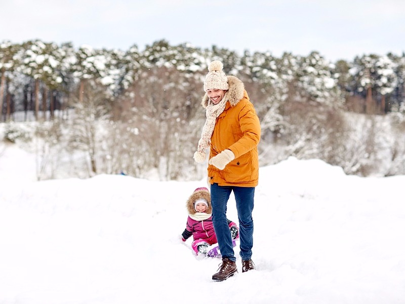 Daddy pulling daughter in a sled