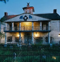 white house lit up at night with large porch