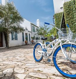 white bike with blue wheel on cobblestone sidewalk of Alys Beach Florida