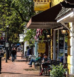 quaint main street with brick lined sidewalks and people sitting in benches