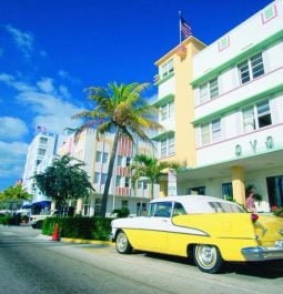 yellow classic car in front of miami hotel