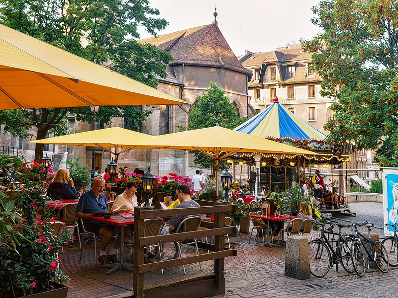 People in street open air restaurant at carousel and Madeleine Church in the old town in Geneva 