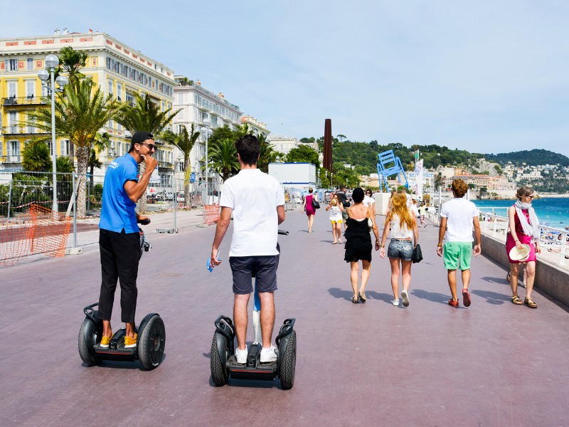 People walking and riding segways at the famous Promenade des Anglais bordering the Mediterranean sea in Nice