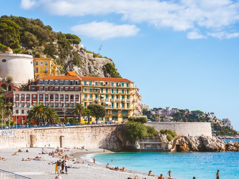 Beautiful architecture and people relaxing on beach that stretches along Promenade des Anglais in Nice