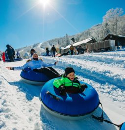 Mother and child in snow tubes going down hill