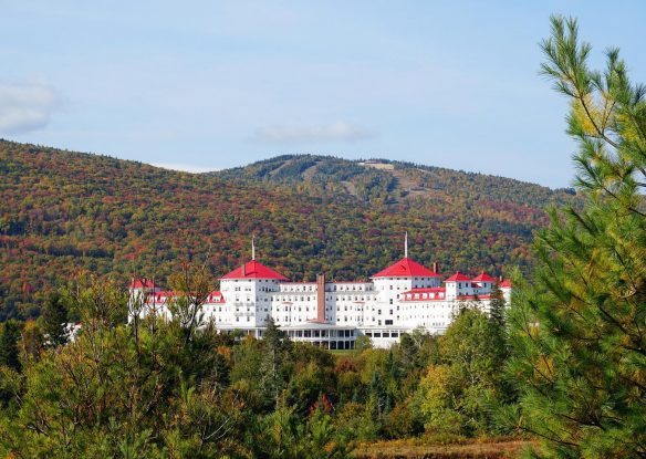 new england resort atop a hill surrounded by mountains and forest