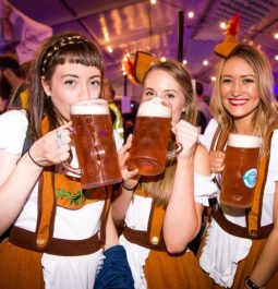 three people with liters of beer in german attire