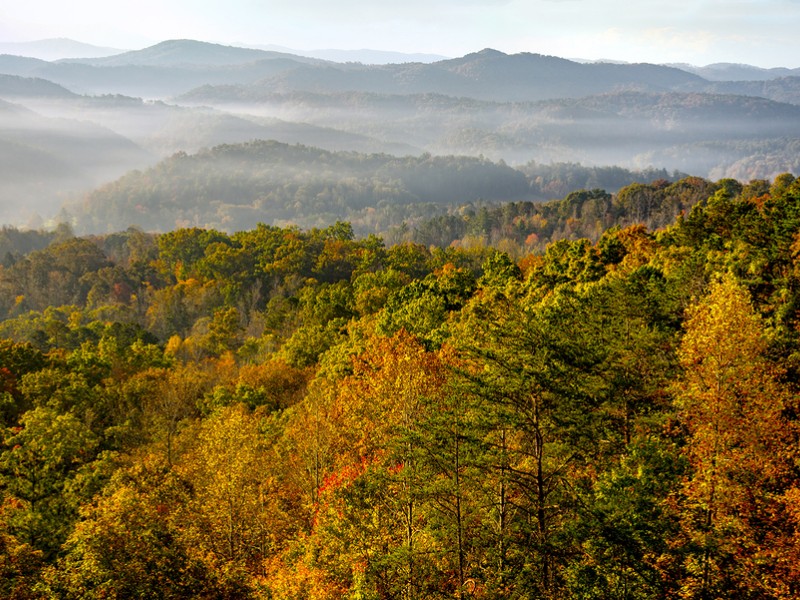 The sun rises over the mountains of Great Smoky Mountains National Park at the peak of autumn's colors