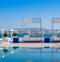 pool cabanas and loungers sit around pool overlooking blue sea