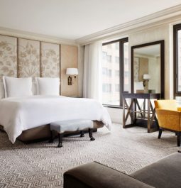 luxury hotel room with yellow chair and artwork behind the bed