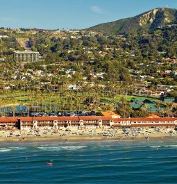 aerial view of beachfront resort with grassy mountain behind