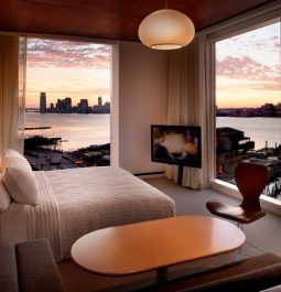 corner hotel suite with views of new york city across a body of water