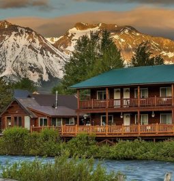 exterior view of hotel along river with snowcapped mountains