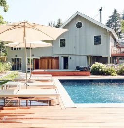 Wooden pool deck with loungers and umbrella and house in background