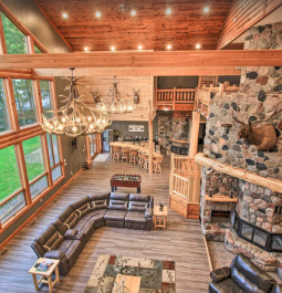 spacious living area with stone fireplace and floor-to-ceiling windows