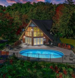 Aerial view of a cabin with large windows and a private pool tucked in the mountains of Gatlinburg at sunset