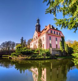 Pink toned castle on glassy lake with bright blue skies