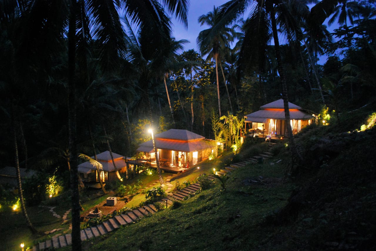 Tents at night in the jungle illuminated in the distance 