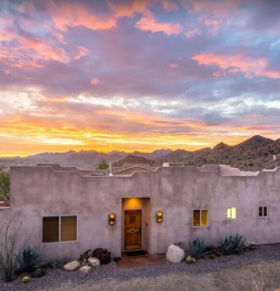 Cement Western style home in desert setting with beautiful sunset in background