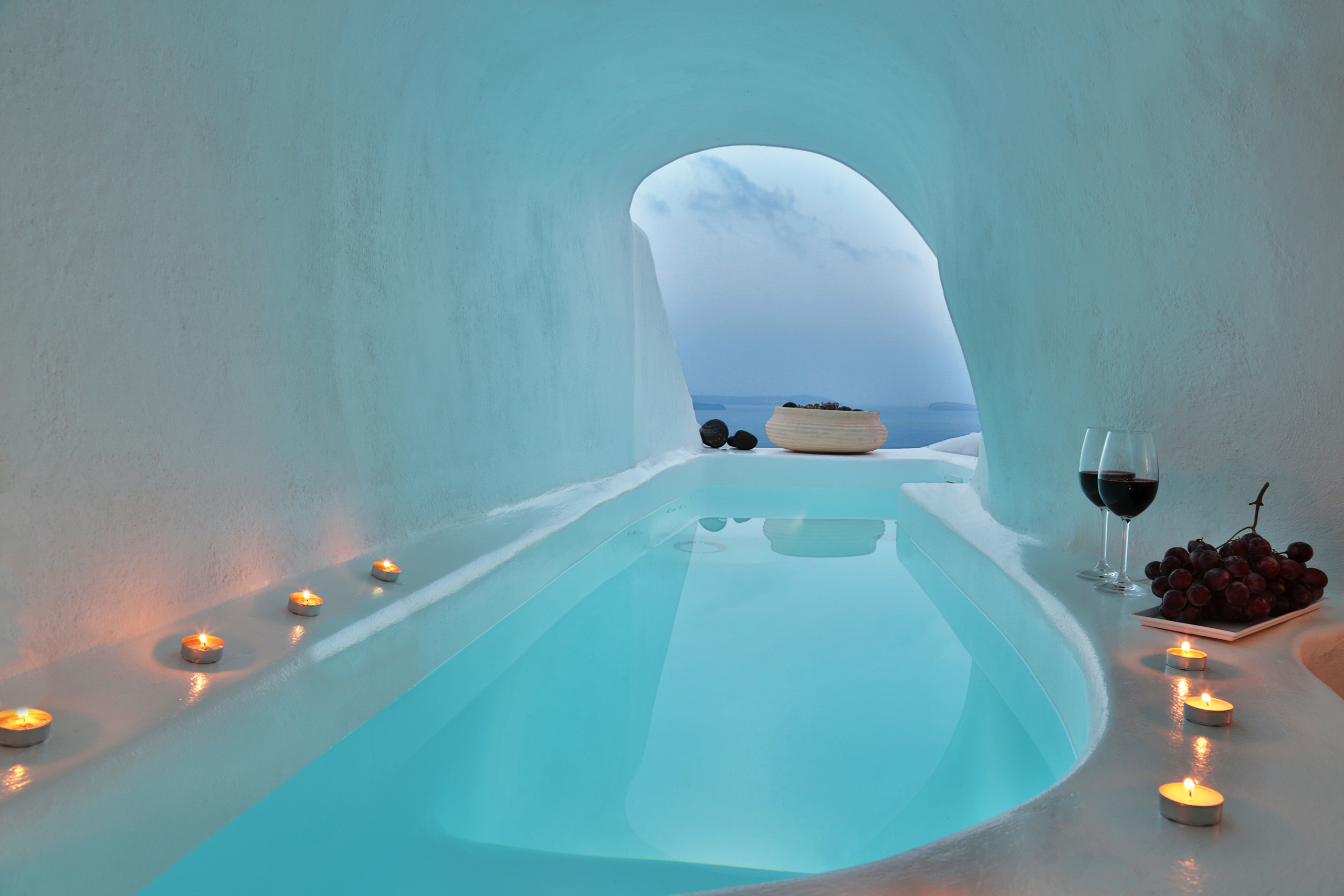 Aquamarine jacuzzi with wine glasses inside cave