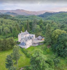 Aerial view of 16th-century Scottish castle surrounded by trees and hills