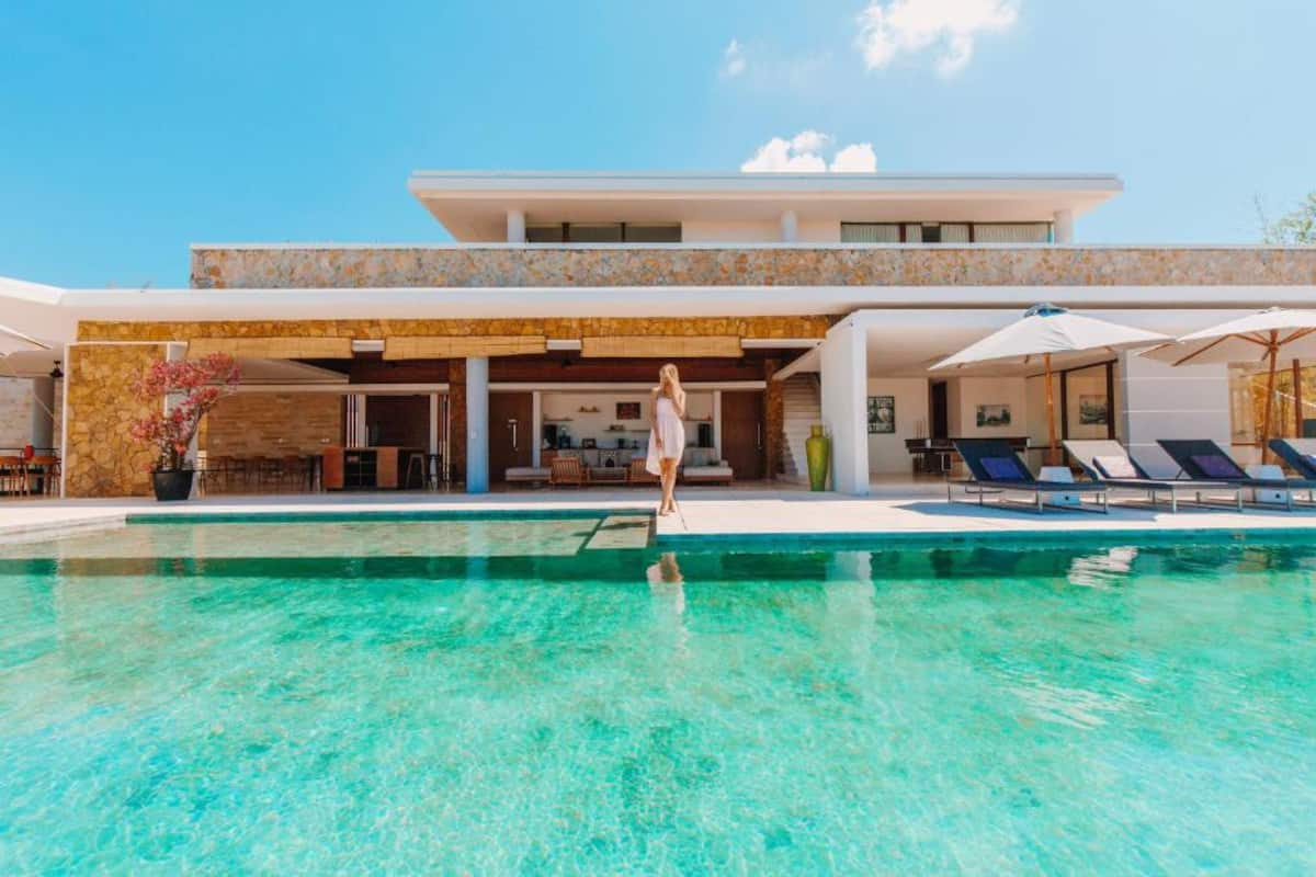 Vibrant blue infinity pool with sandstone villa behind