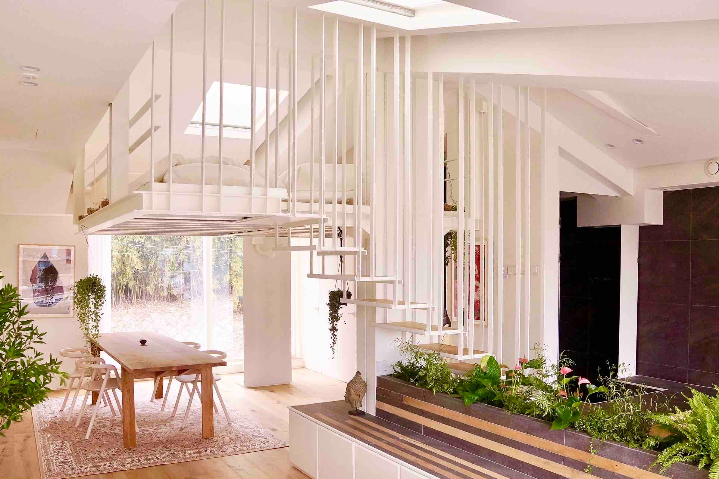 Open plan white living space with decorative staircase cascading down the middle