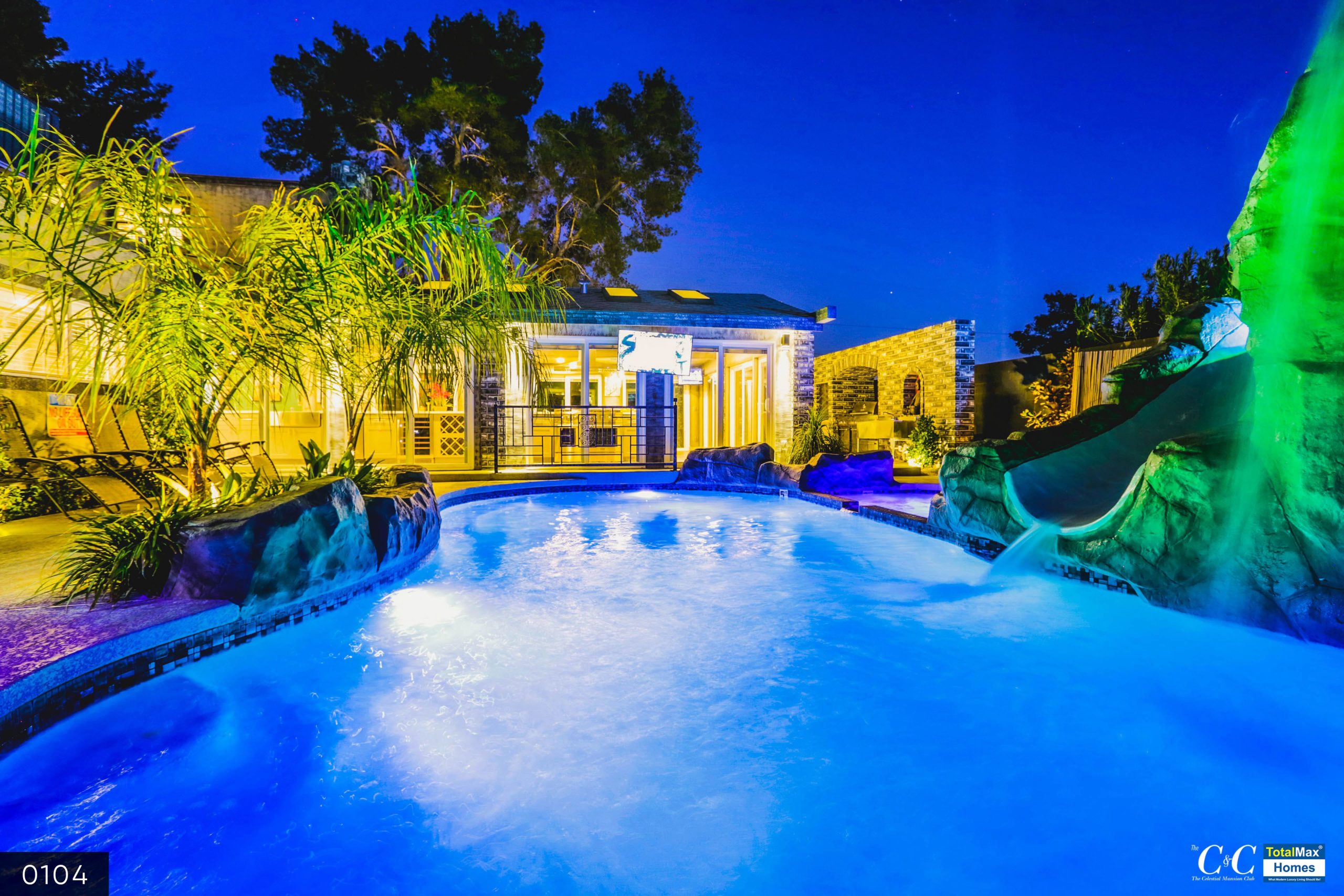 Floodlit swimming pool with rainbow lights across the plants