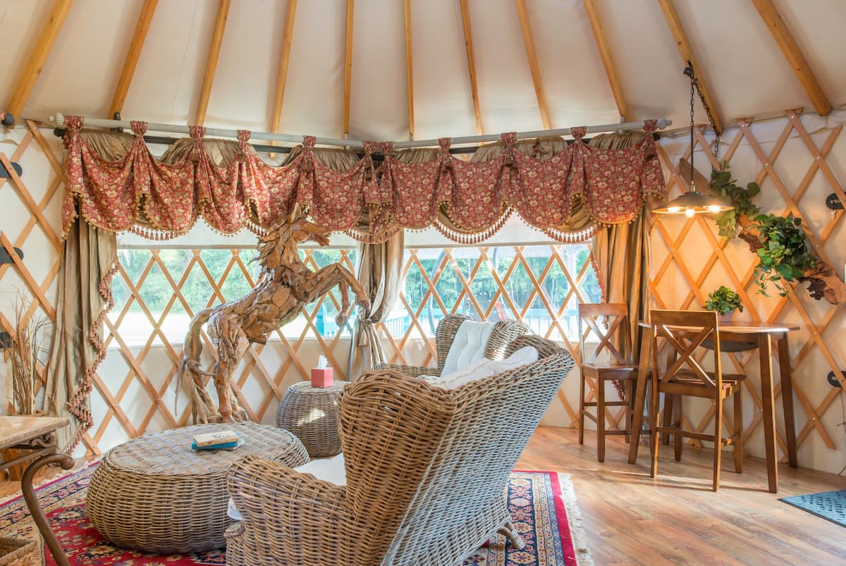 Cozy, traditional yurt interiors with comfy chairs and hanging curtains