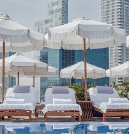 Rooftop swimming pool with sunbeds and skyscrapers in the background