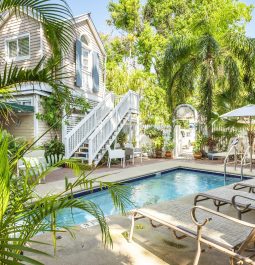 Lush outdoor area with a swimming pool next to a hotel